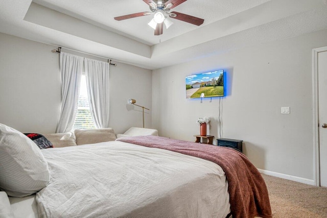 bedroom with carpet flooring, ceiling fan, and a tray ceiling