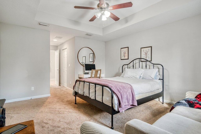 bedroom with a raised ceiling, carpet floors, and ceiling fan