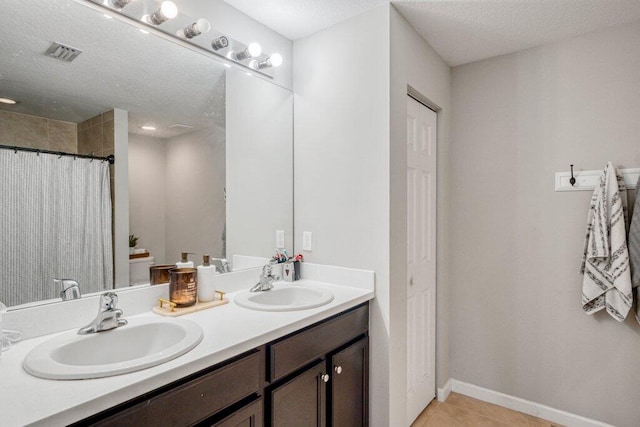 bathroom featuring tile patterned floors, vanity, and a textured ceiling