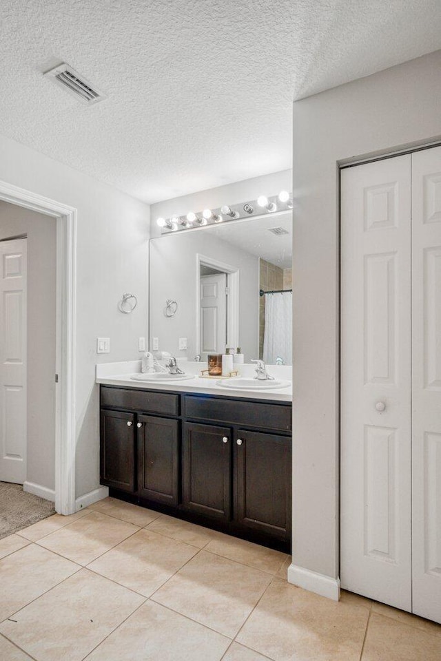 bathroom with vanity, tile patterned flooring, and a textured ceiling