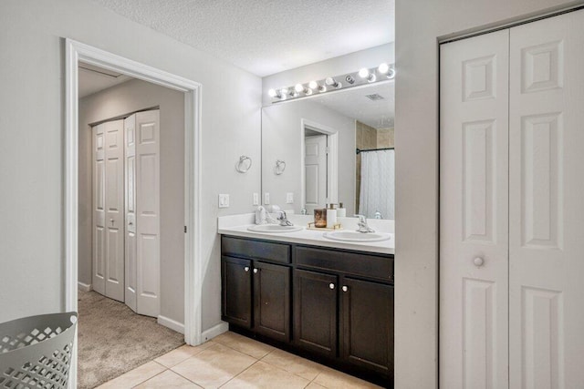 bathroom with vanity, tile patterned flooring, a textured ceiling, and walk in shower