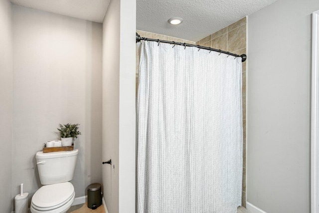 bathroom with a textured ceiling, toilet, and a shower with shower curtain