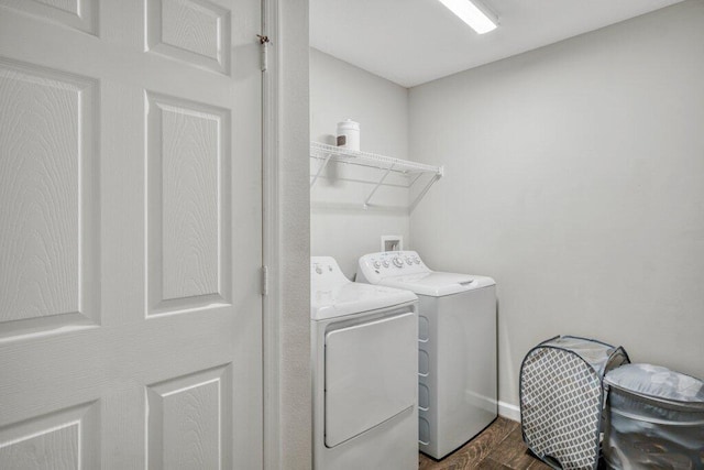 clothes washing area with dark wood-type flooring and washer and clothes dryer