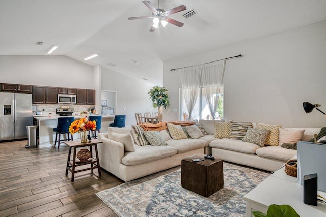 living room with dark wood-type flooring, ceiling fan, and high vaulted ceiling