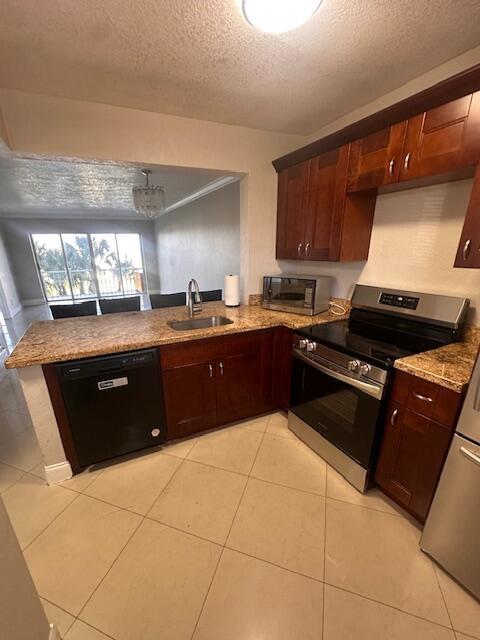 kitchen with light tile patterned flooring, sink, a textured ceiling, kitchen peninsula, and stainless steel appliances