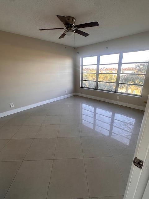 tiled spare room featuring ceiling fan and a textured ceiling