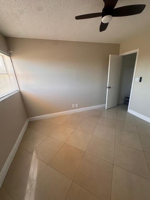 unfurnished room with ceiling fan, a textured ceiling, and light tile patterned floors