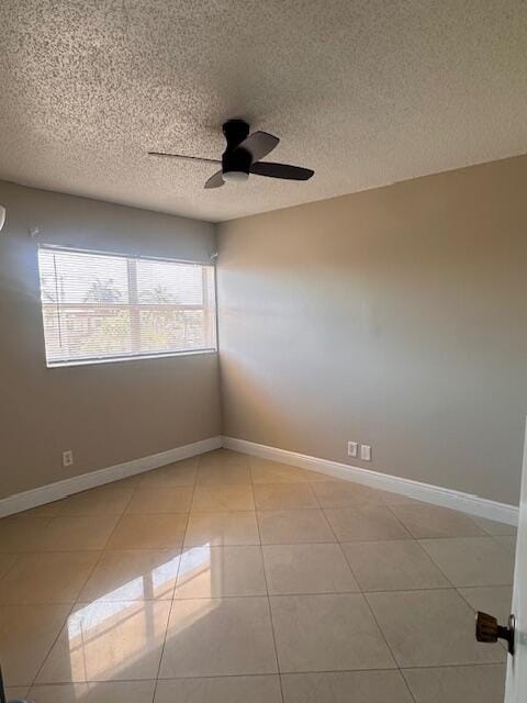 empty room with a textured ceiling, ceiling fan, and light tile patterned flooring