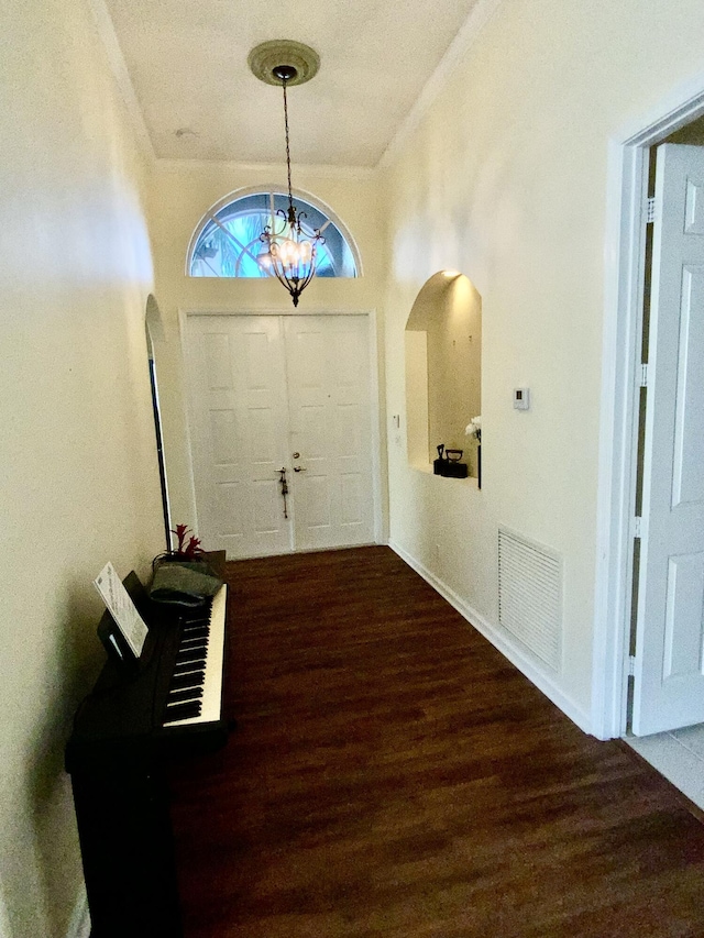 foyer with hardwood / wood-style flooring, ornamental molding, and a chandelier