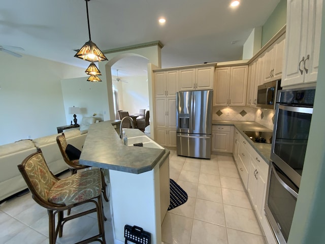 kitchen with sink, tasteful backsplash, appliances with stainless steel finishes, pendant lighting, and ceiling fan