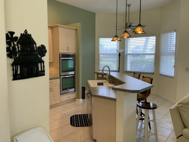 kitchen with appliances with stainless steel finishes, a breakfast bar, decorative light fixtures, sink, and a kitchen island with sink