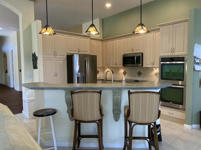 kitchen with an island with sink, appliances with stainless steel finishes, and a breakfast bar area