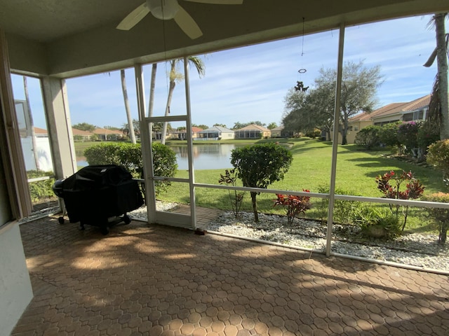 sunroom with a wealth of natural light, ceiling fan, and a water view