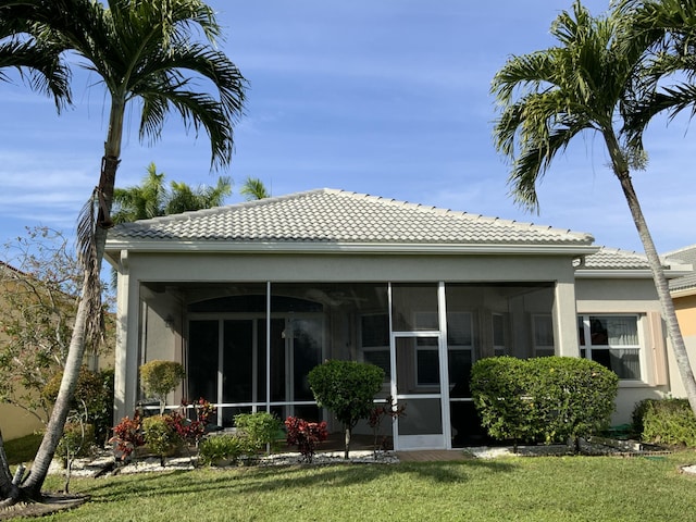 back of property with a sunroom and a lawn