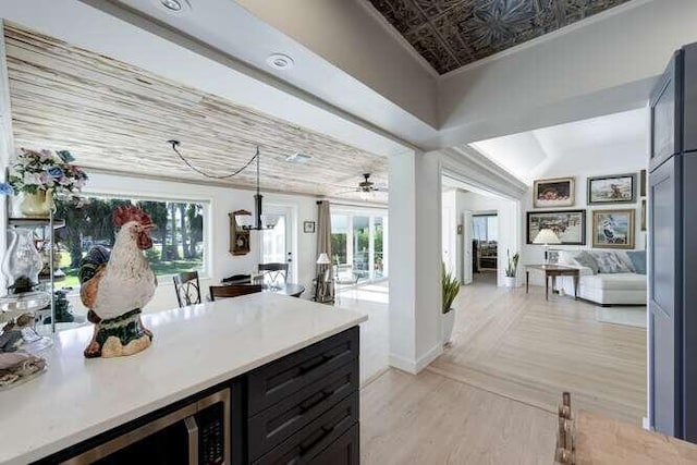 kitchen with crown molding, decorative light fixtures, and light hardwood / wood-style flooring