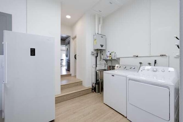 laundry area featuring water heater, separate washer and dryer, and light hardwood / wood-style flooring