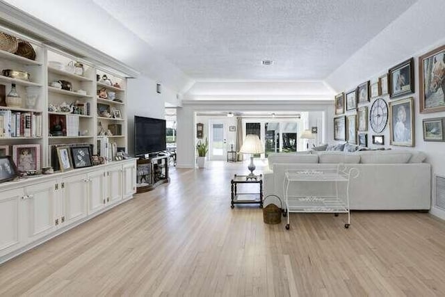 living room featuring a tray ceiling, a textured ceiling, and light hardwood / wood-style flooring