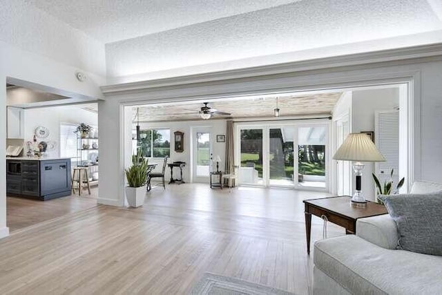 living room with ceiling fan, light hardwood / wood-style flooring, and a textured ceiling