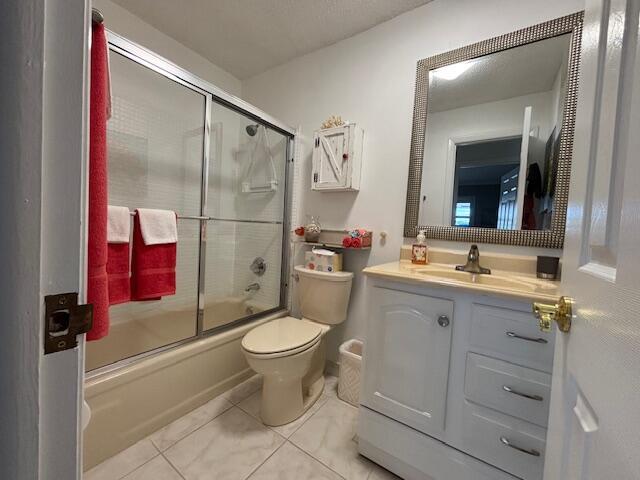 full bathroom with vanity, tile patterned floors, shower / bath combination with glass door, and toilet