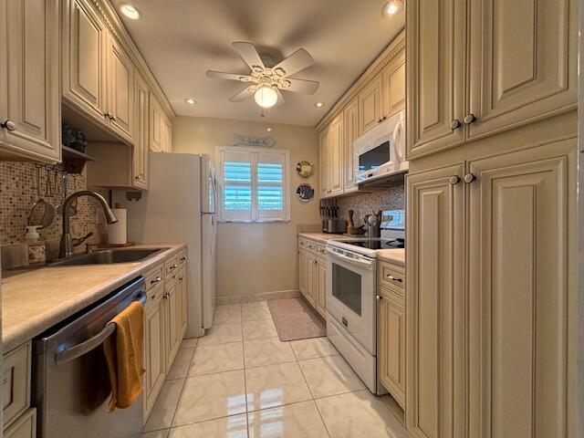 kitchen featuring sink, tasteful backsplash, ceiling fan, white appliances, and cream cabinets