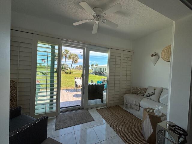 entryway with ceiling fan, a textured ceiling, and light tile patterned flooring