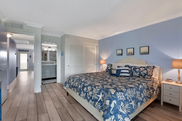 bedroom with crown molding, light wood-type flooring, a closet, and ensuite bathroom