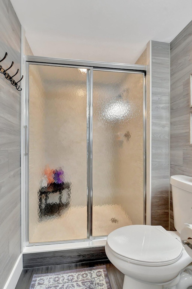 bathroom with walk in shower, toilet, and hardwood / wood-style flooring