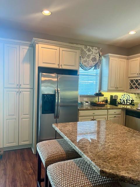 kitchen with white cabinetry, dark hardwood / wood-style flooring, stainless steel appliances, and stone countertops