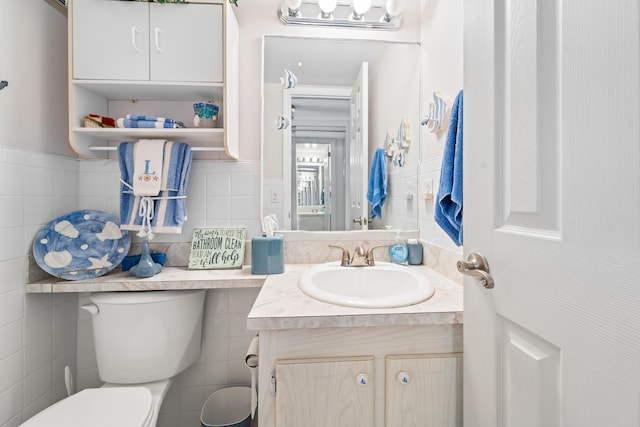 bathroom featuring vanity, tile walls, and toilet