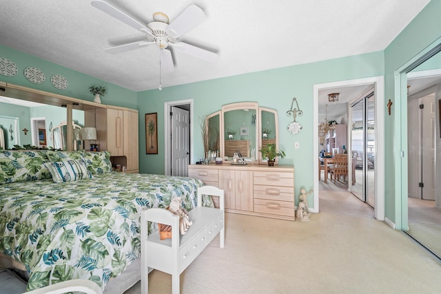 bedroom with ceiling fan, light colored carpet, and a textured ceiling