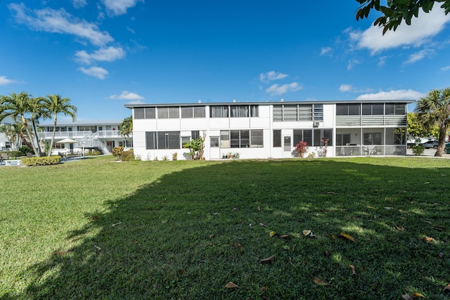 rear view of house featuring a sunroom and a lawn