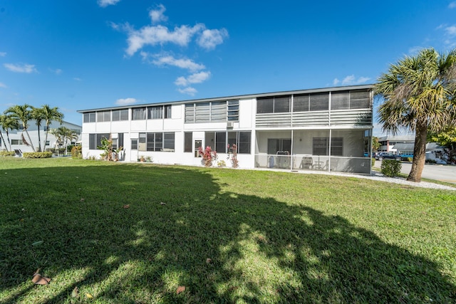 back of property featuring a sunroom and a lawn