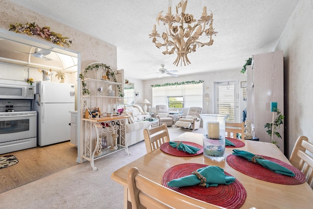 dining space with ceiling fan with notable chandelier, a textured ceiling, and light wood-type flooring