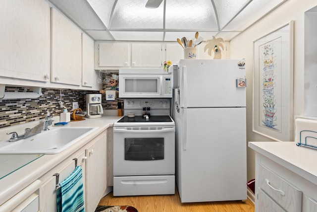 kitchen with sink, a paneled ceiling, white appliances, light hardwood / wood-style floors, and backsplash