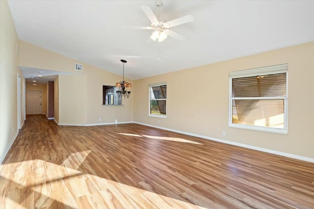 unfurnished room featuring vaulted ceiling, ceiling fan with notable chandelier, and light hardwood / wood-style flooring