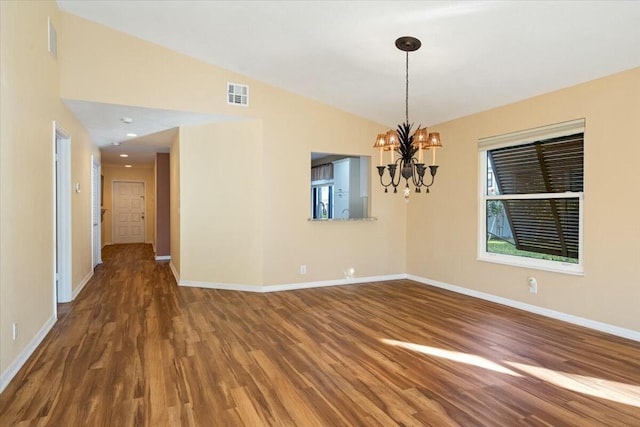 spare room featuring a notable chandelier, vaulted ceiling, and dark hardwood / wood-style floors