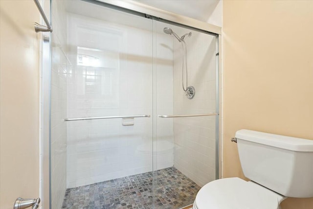 bathroom with a shower with door and toilet