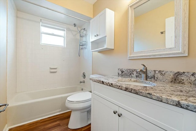 full bathroom featuring tiled shower / bath combo, wood-type flooring, vanity, and toilet