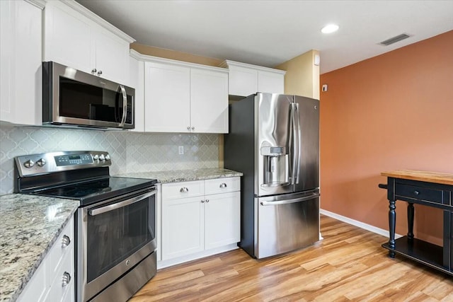 kitchen with stainless steel appliances, white cabinetry, light wood-type flooring, and decorative backsplash