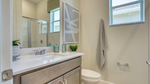 bathroom featuring vanity, a shower with shower door, and toilet