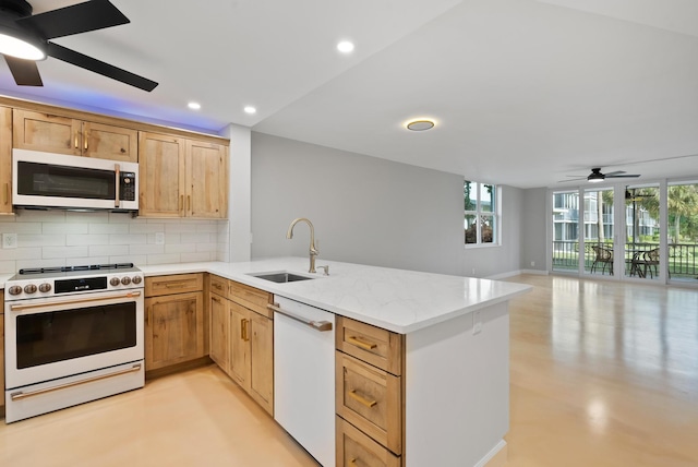 kitchen with tasteful backsplash, sink, kitchen peninsula, light stone countertops, and white appliances