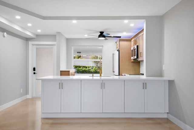 kitchen featuring white refrigerator, ceiling fan, white cabinetry, and sink