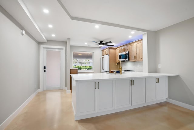 kitchen featuring light brown cabinetry, backsplash, high end white fridge, and kitchen peninsula