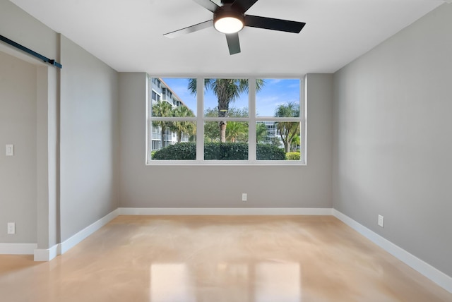 unfurnished bedroom featuring a barn door and ceiling fan