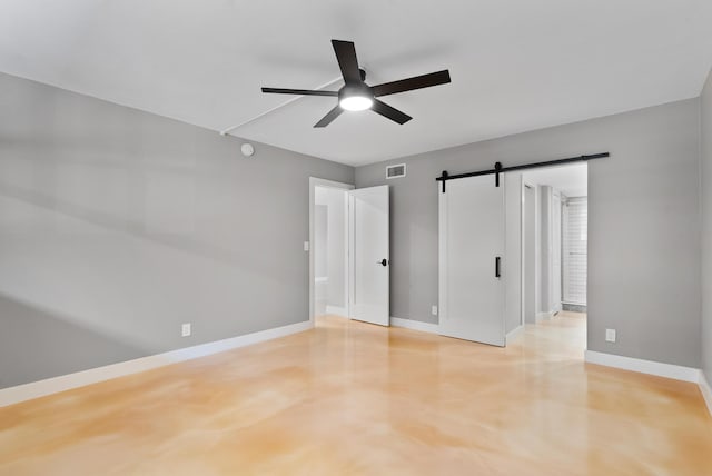 unfurnished bedroom with concrete flooring, a barn door, and ceiling fan