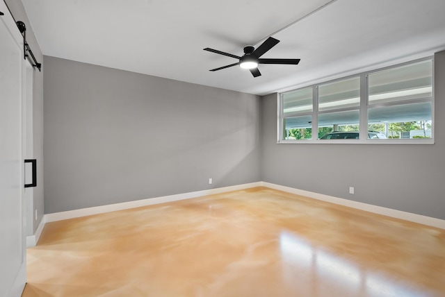 empty room with concrete floors, a barn door, and ceiling fan