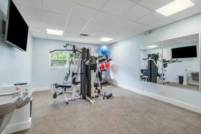 workout room with a paneled ceiling and light carpet