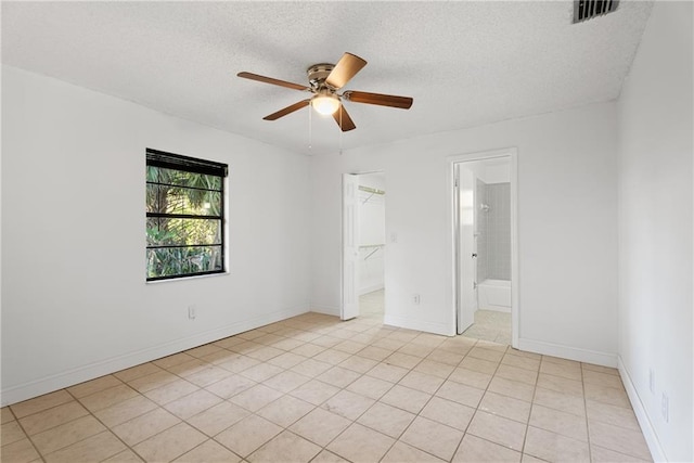 spare room featuring ceiling fan, a textured ceiling, and light tile patterned floors