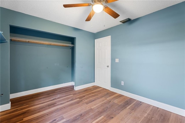 unfurnished bedroom with wood-type flooring, a textured ceiling, ceiling fan, and a closet