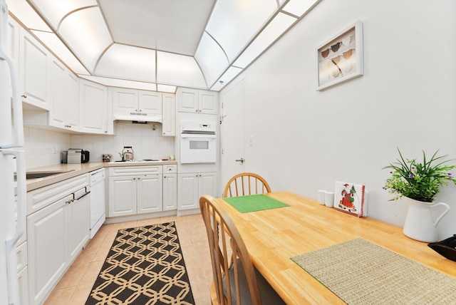 kitchen with white cabinetry, tasteful backsplash, vaulted ceiling, light tile patterned floors, and white appliances